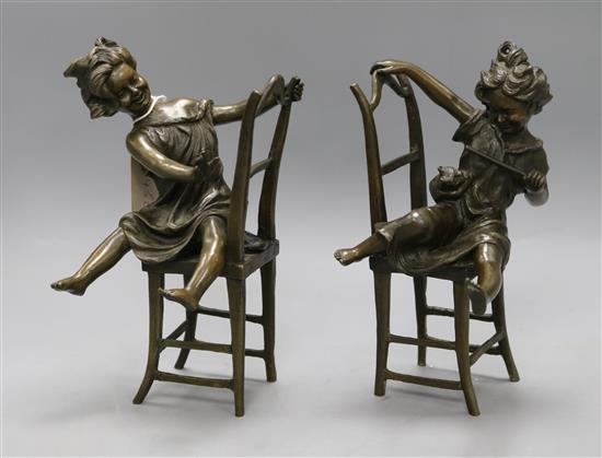 A pair of novelty bronze bookends of girls playing on chairs height 20cm